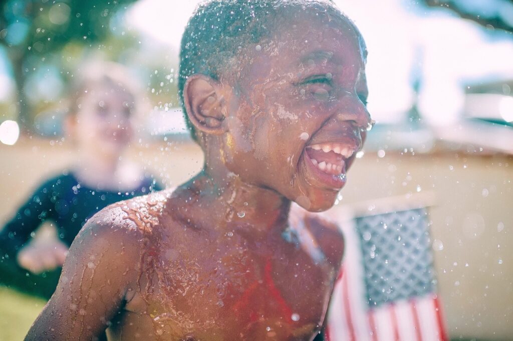Boy running through sprinkler water in summer