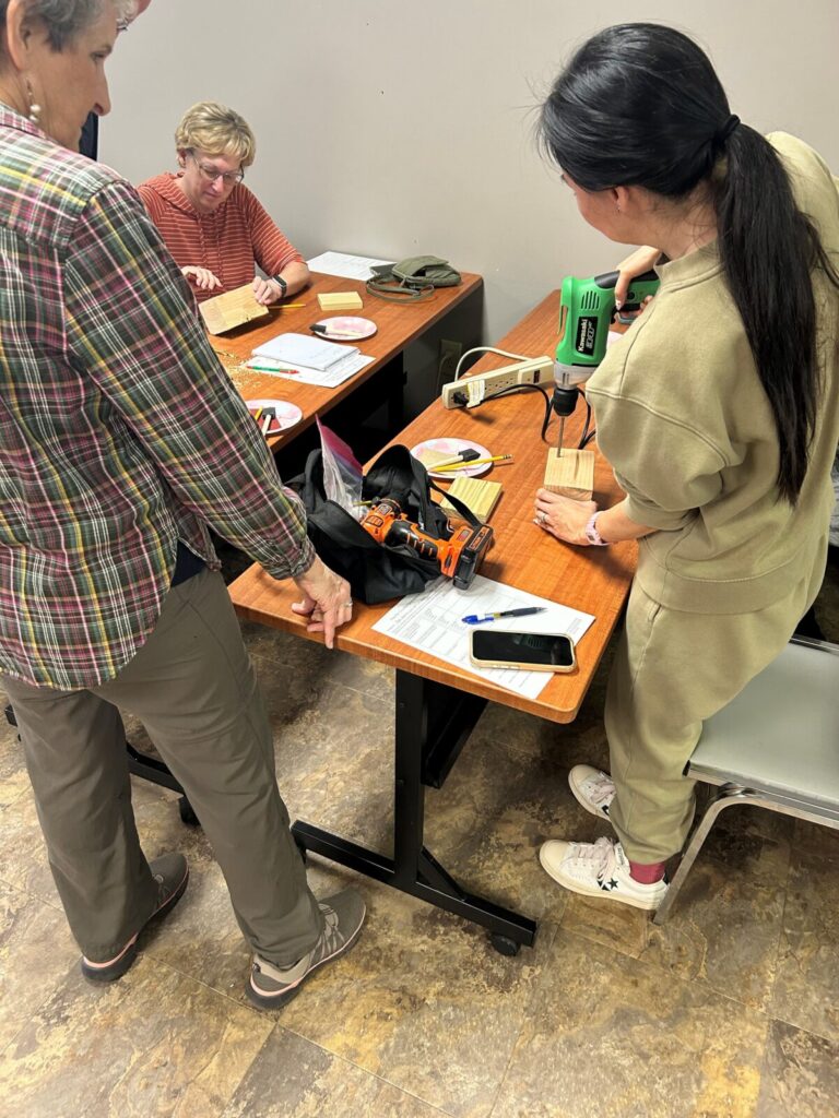 Adult using a drill to make holes in wood block.