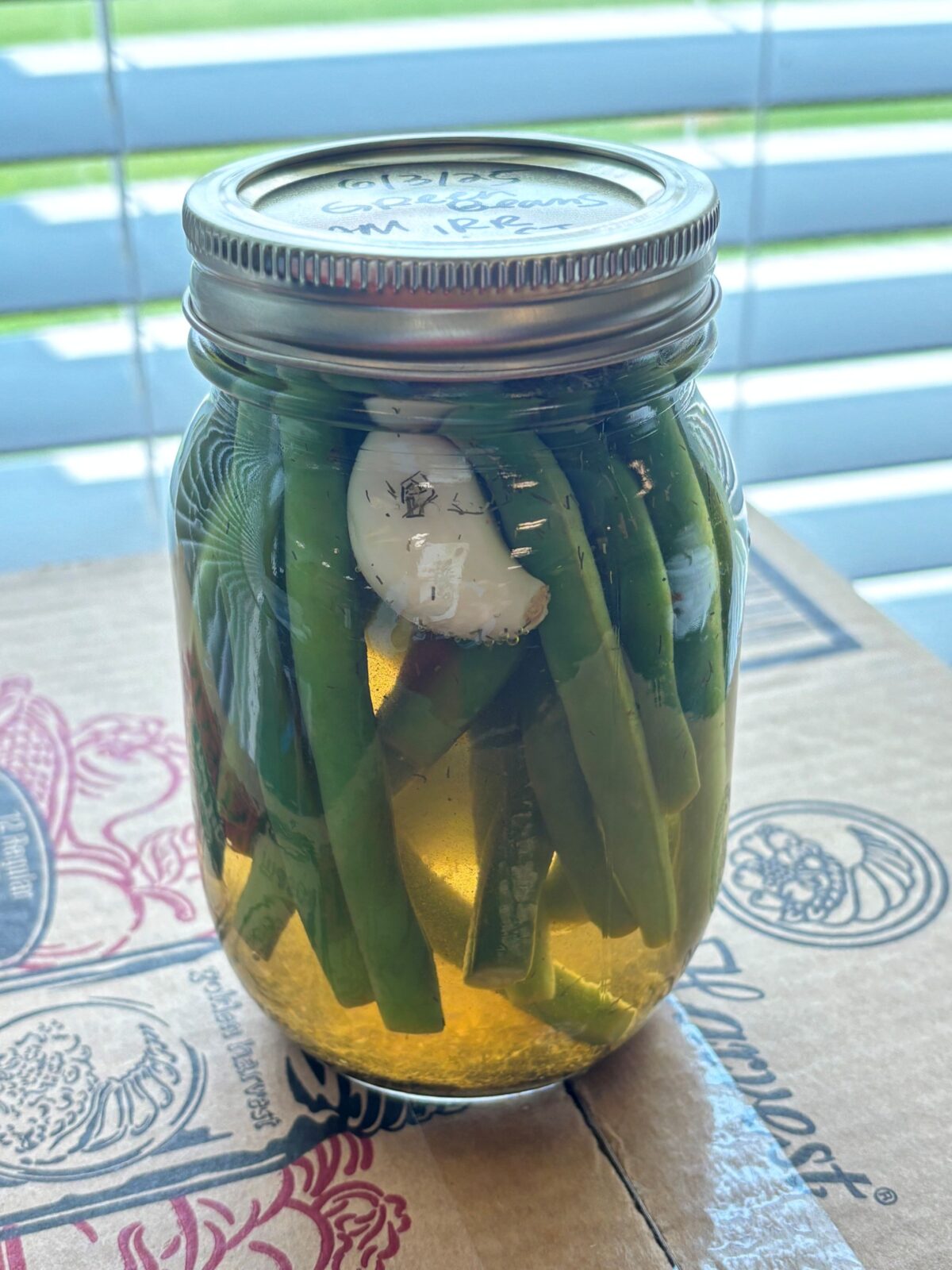 A canning jar with green beans and garlic inside