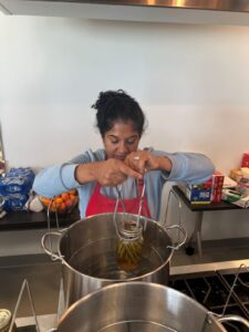 An adult woman lifting a jar of canned green beans from a large pot of boiling water