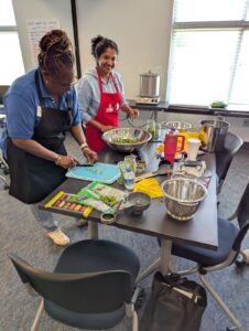 Two women working at a table with kitchen bowls and tools and fresh green beans