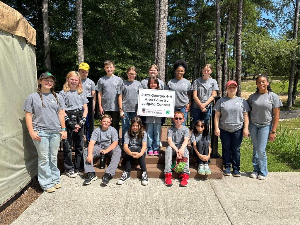 A group of 15 4th-12th grade students posing in front of a sign that says 2025 Georgia 4-H Area Forestry Judging Contest