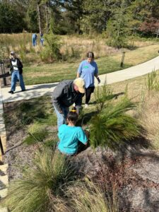 A few youth and an adult cleaning up an outdoor green space.