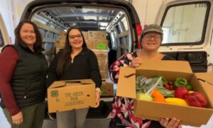 3 adult women holding boxes of fresh produce