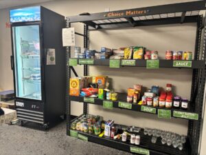 Cans and packages of food stacked on shelves and cooler- Client-choice Pantry Model displays food items like in a grocery store