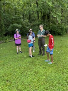 Students and adult learning how to use a compass.