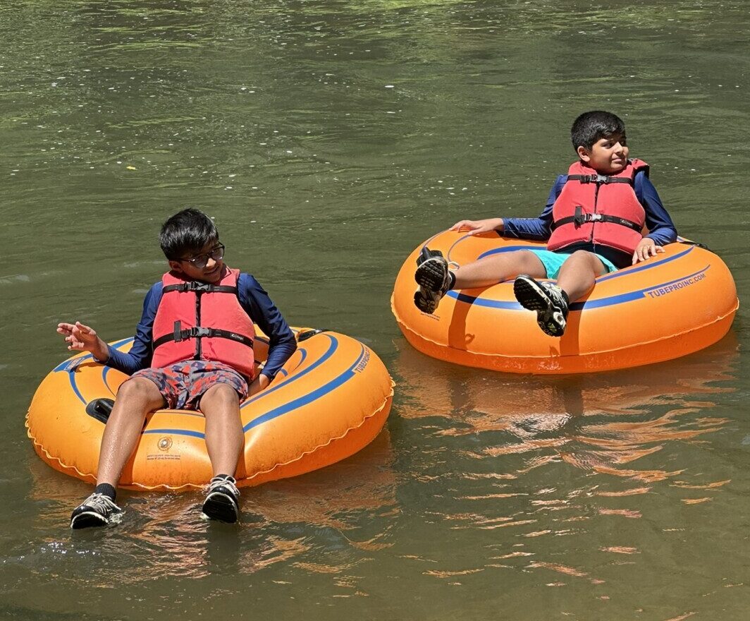 Two kids floating down the river in innertubes.