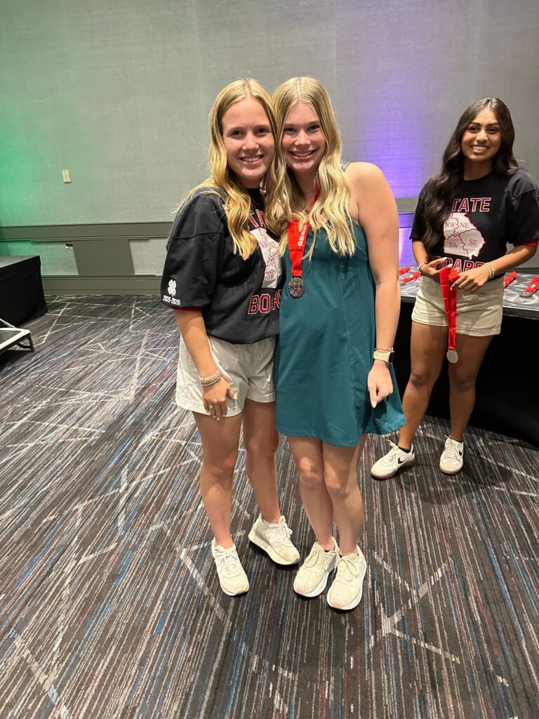4-H student posing with another student, wearing her 2nd place medal