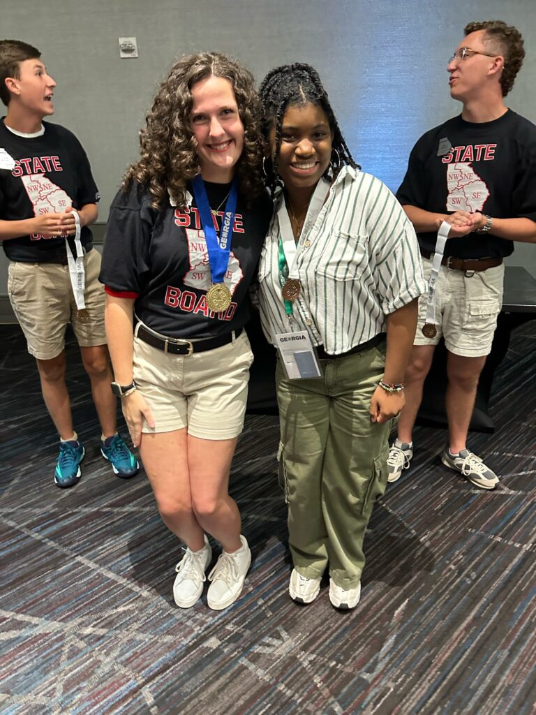 4-H student posing with another student, wearing her 3rd place medal