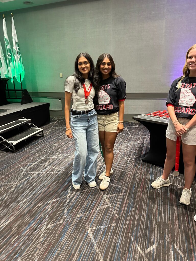 4-H student posing with another student, wearing her 2nd place medal