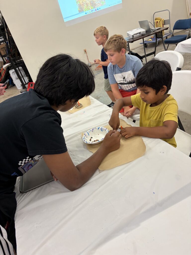 A teen teacher working with a small student on an art project.