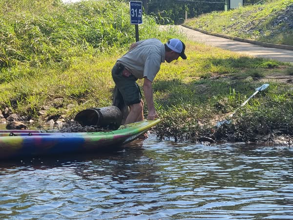 Volunteer removing kayak and trash from the river