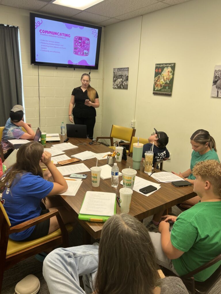young teen girl in front of screen talking to five youth