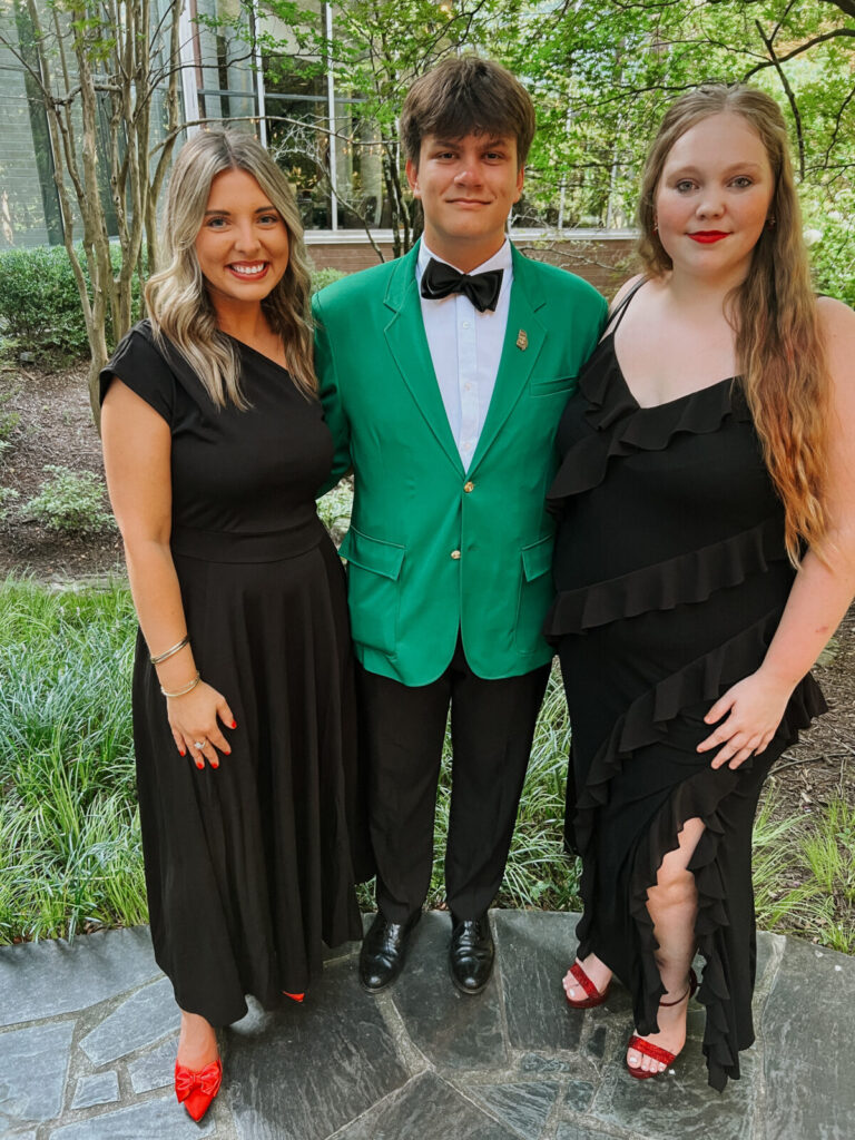 adult leader standing next to a male teen and female teen wearing formal attire
