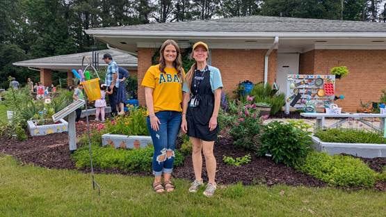 Two women standing in front of a colorful garden