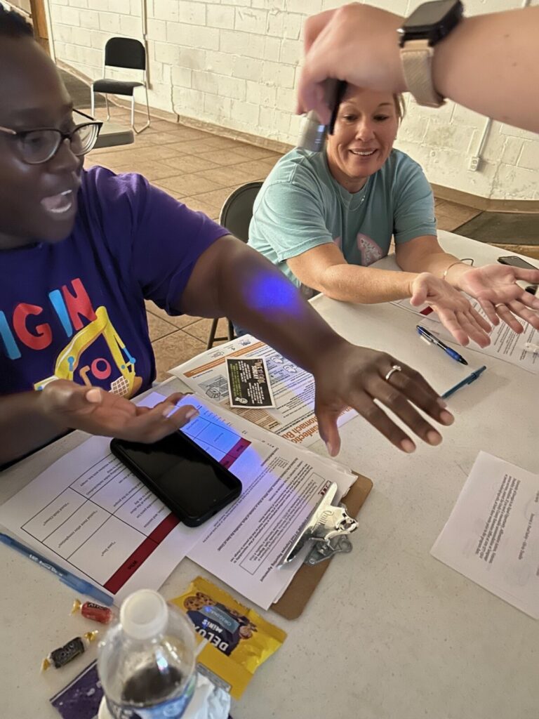 School nutrition works sees glow germ powder light up on their arm.